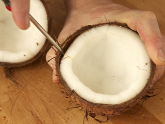 Removing the flesh of the coconut with a screwdriver